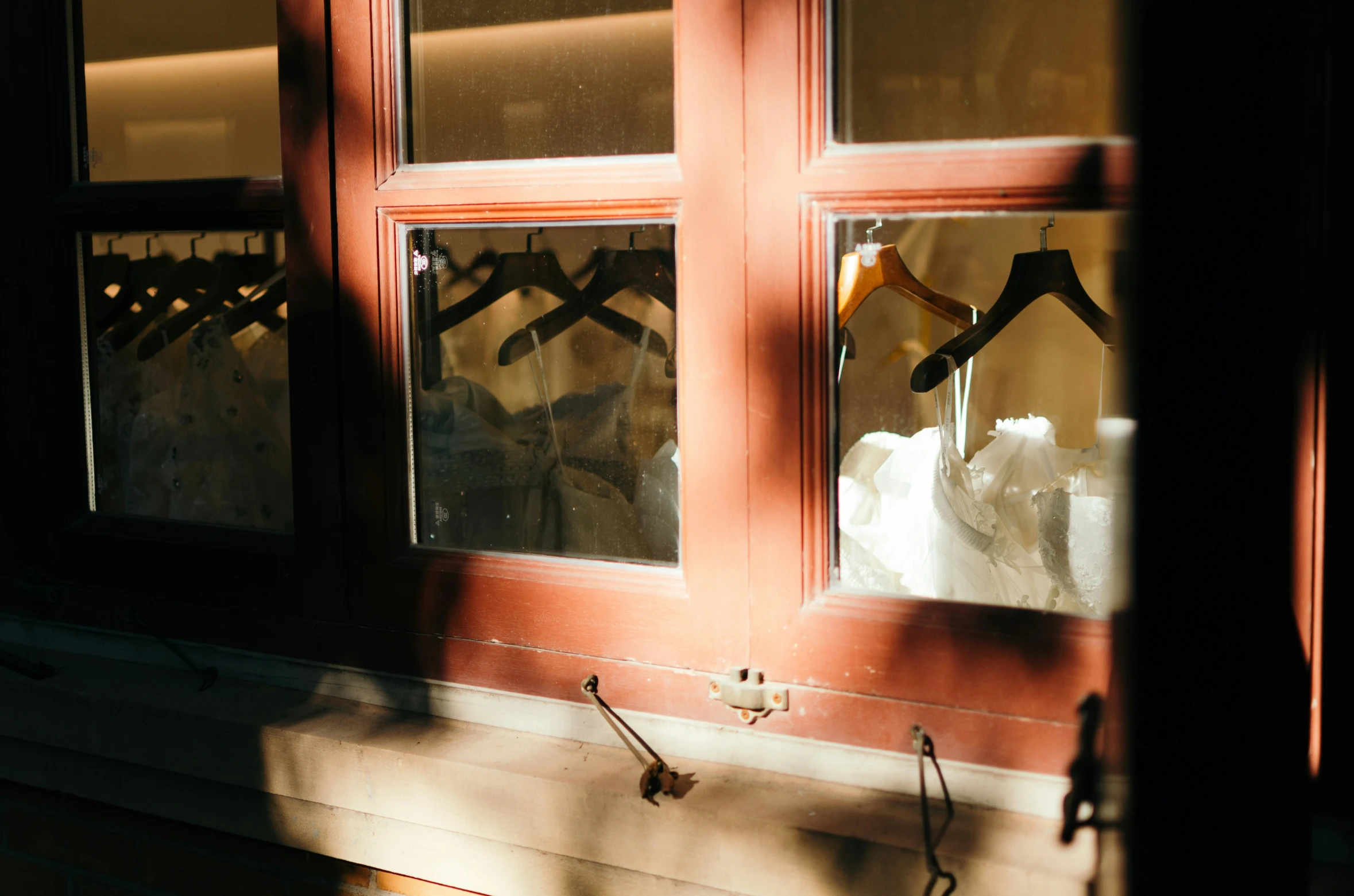 three different bridal gowns hanging in a window