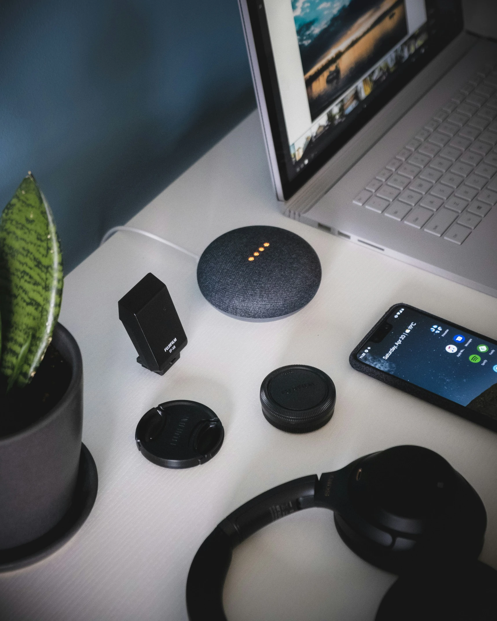 a desktop with an iphone, headphones, smartphone and a cactus