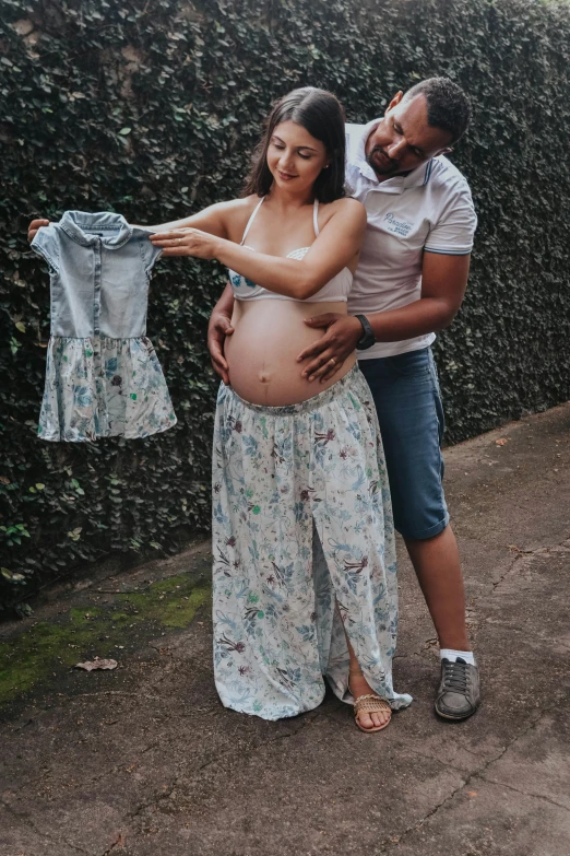 a pregnant woman holds her husband's blue shirt
