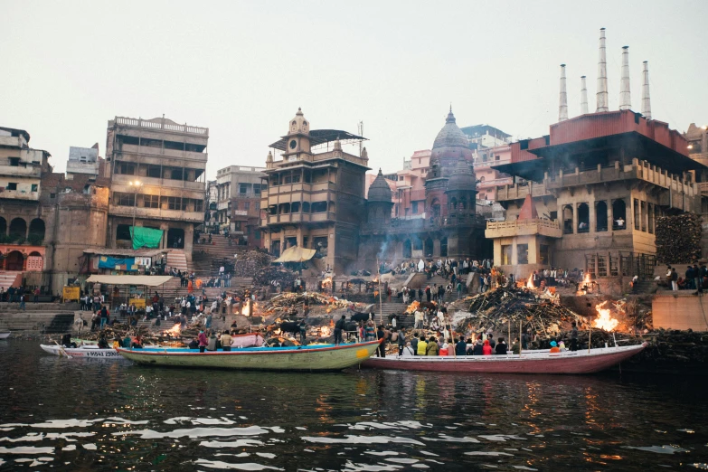 two boats sit on the water in front of a large group of buildings