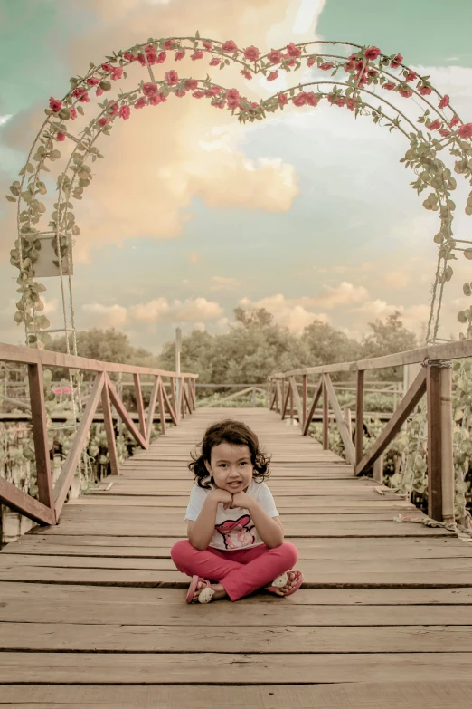 little girl sitting on a bridge in the daytime