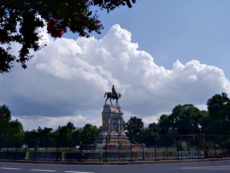 a statue with a person sitting on a horse in front of the monument