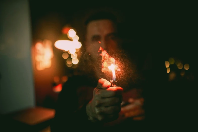 man holding lighter in dark room with dark walls