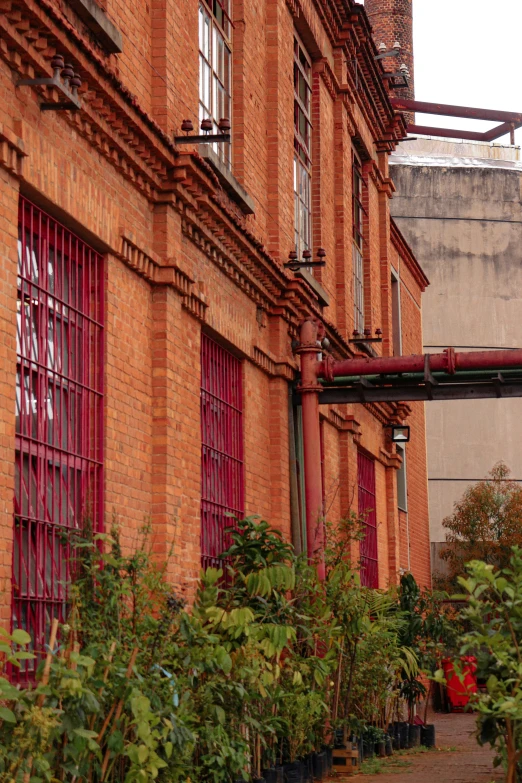 a red brick building with green plants in front of it