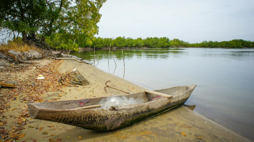 a small boat sitting on the shore of a lake