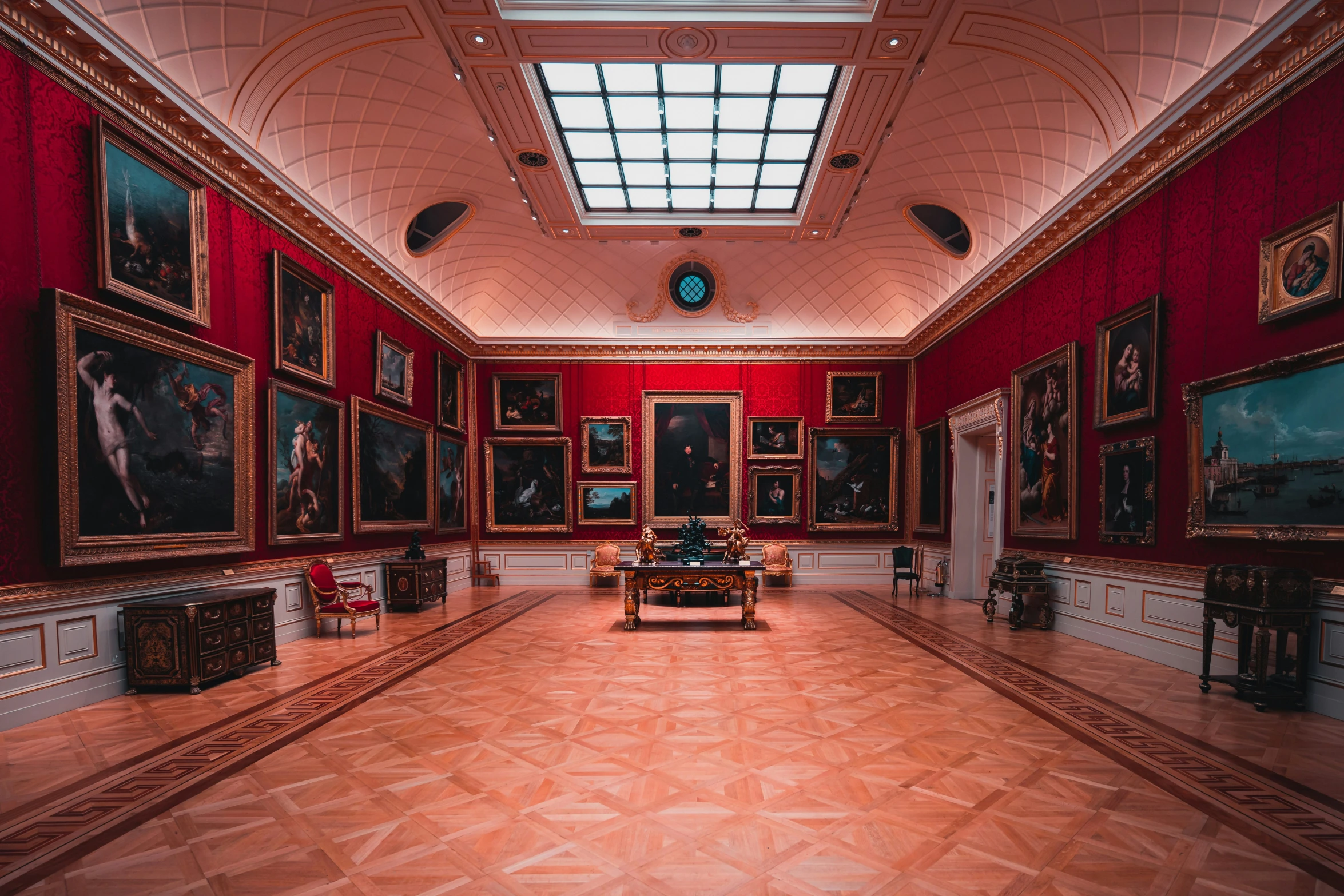 a room with various paintings on it, two tables and a vase