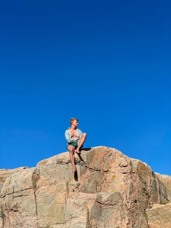 a man sitting on top of a large stone pillar