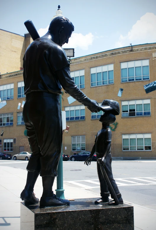 a small statue of a boy playing baseball next to a man holding a bat