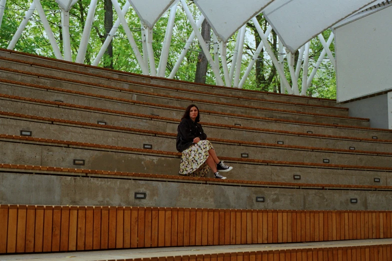 a woman sitting on a ledge in front of a row of chairs