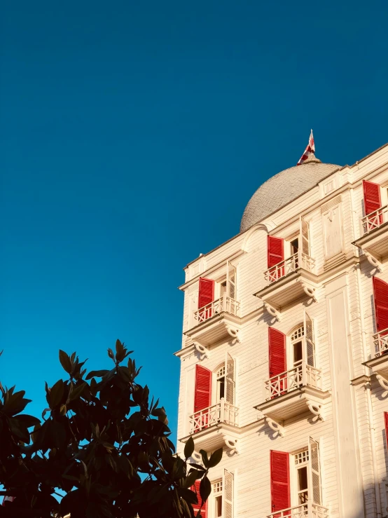 an ornate building with red shutters stands under a blue sky