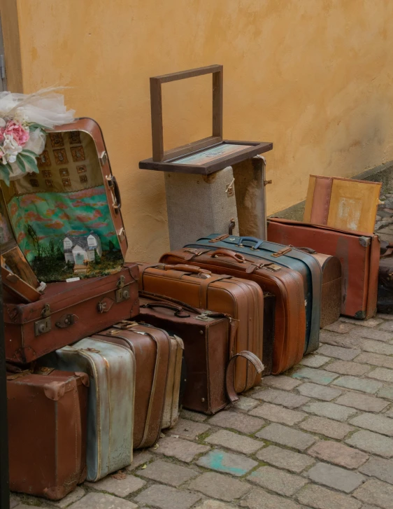 several suitcases in front of a yellow wall on the sidewalk