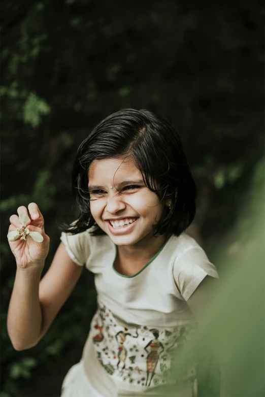 a girl is holding a flower outside in her hand