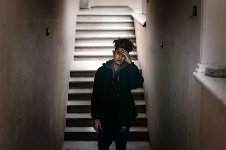 a man wearing a green hoodie stands on the bottom stairs of stairs