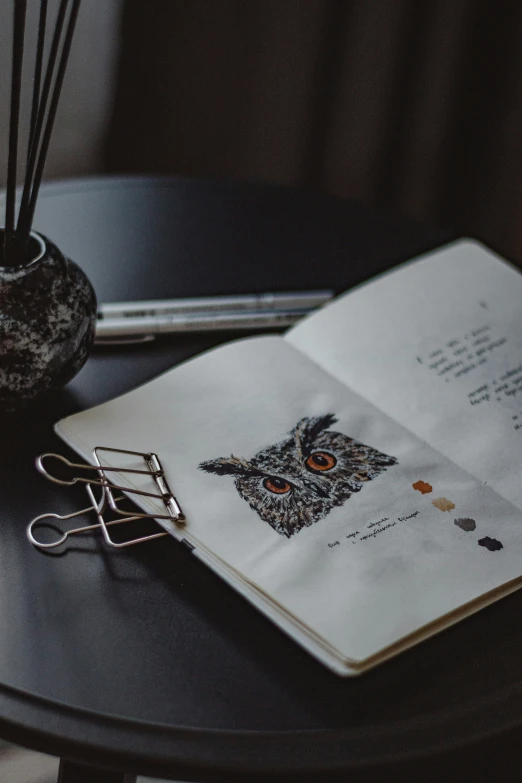 an open book and pen sitting on a small table