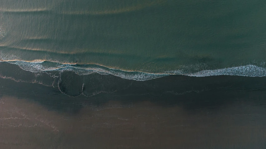 a view from above of the water, with a plane flying over the water and land behind the water