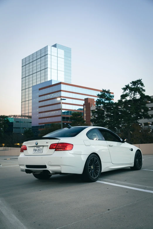 a white bmw in a parking lot with skyscrs in the background