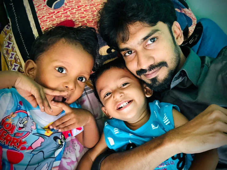 a father holding two children who are smiling at the camera