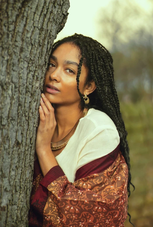 a girl with dreadlocks is next to a tree