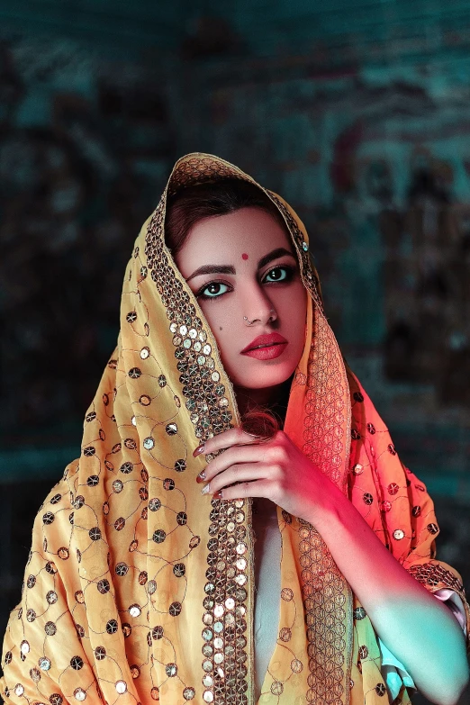 a woman dressed in indian garb stands against a dark background