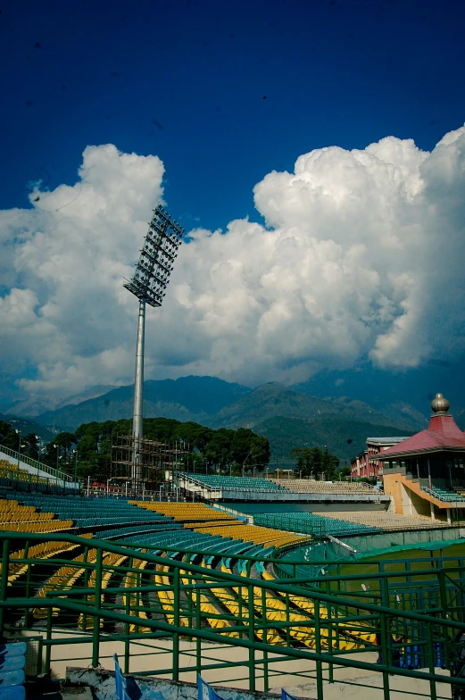 some baseball bleachers and yellow barriers against a sky filled with clouds