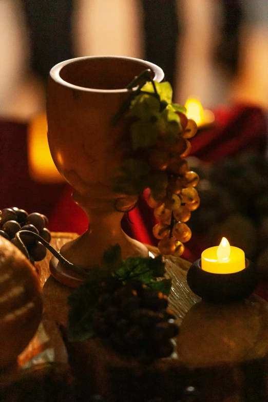 a chalice with a light on it is standing near some flowers and a candle