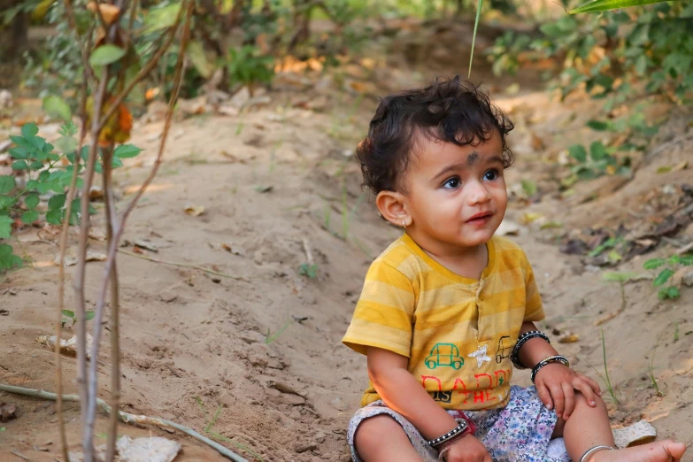 young child in yellow shirt sitting on the ground