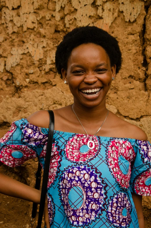 the woman is smiling for the camera in front of a stone wall