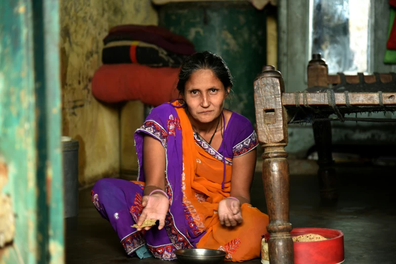 a woman sitting in a room with bowls and a metal pan