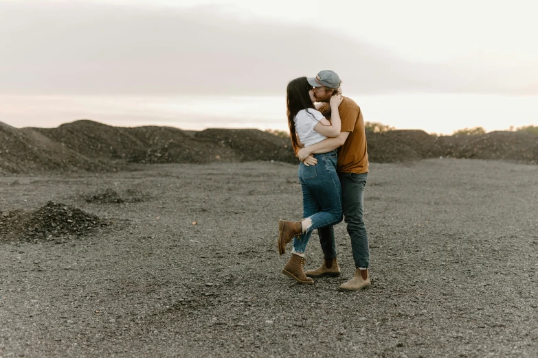 a man and woman hug each other as they stand in an open field