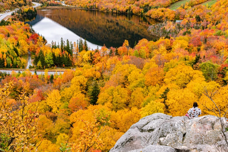 the man is sitting on a rock overlooking the beautiful scenery