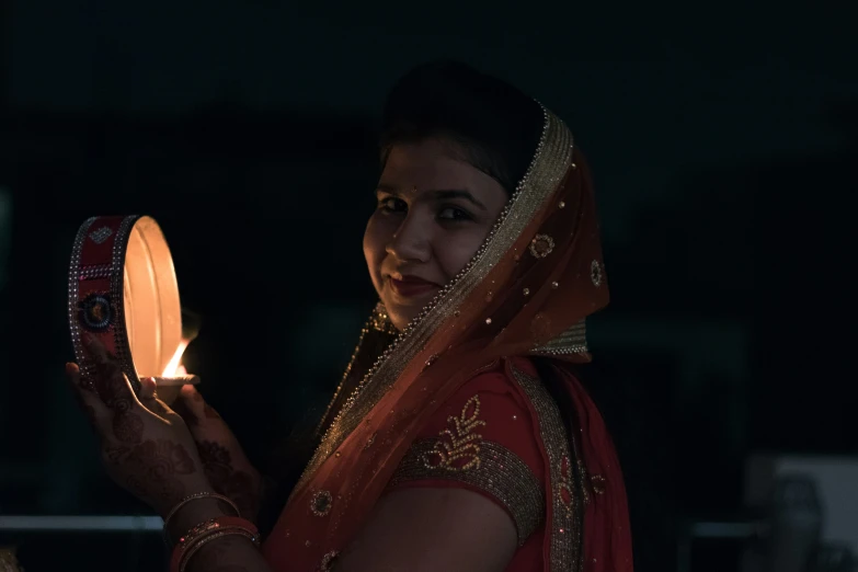 a woman wearing a red sari holding a lighted candle