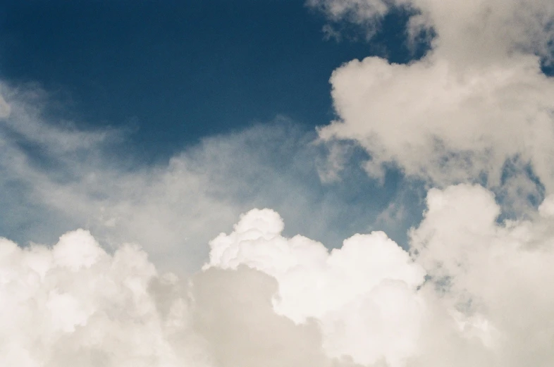 an airplane flies low in the sky with some clouds in the background