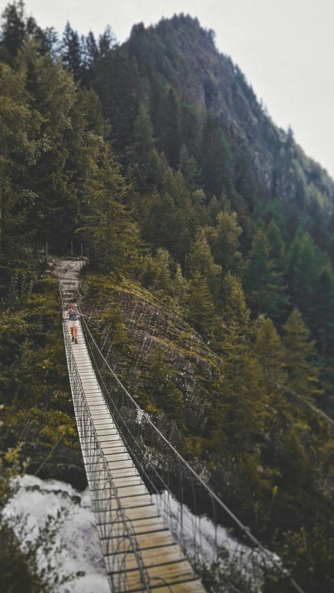 a suspension bridge over a stream next to a mountain