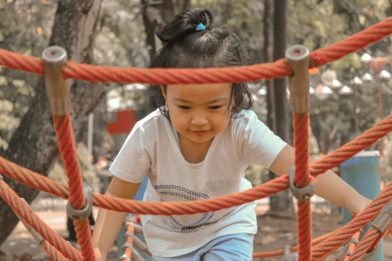 a girl with her arms over the rope on a playground