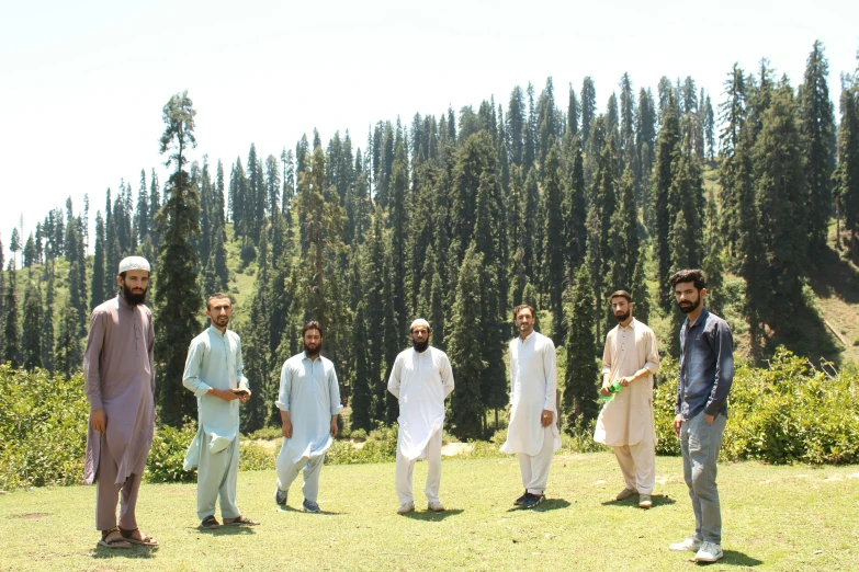 five men standing in an open field with one pointing to soing