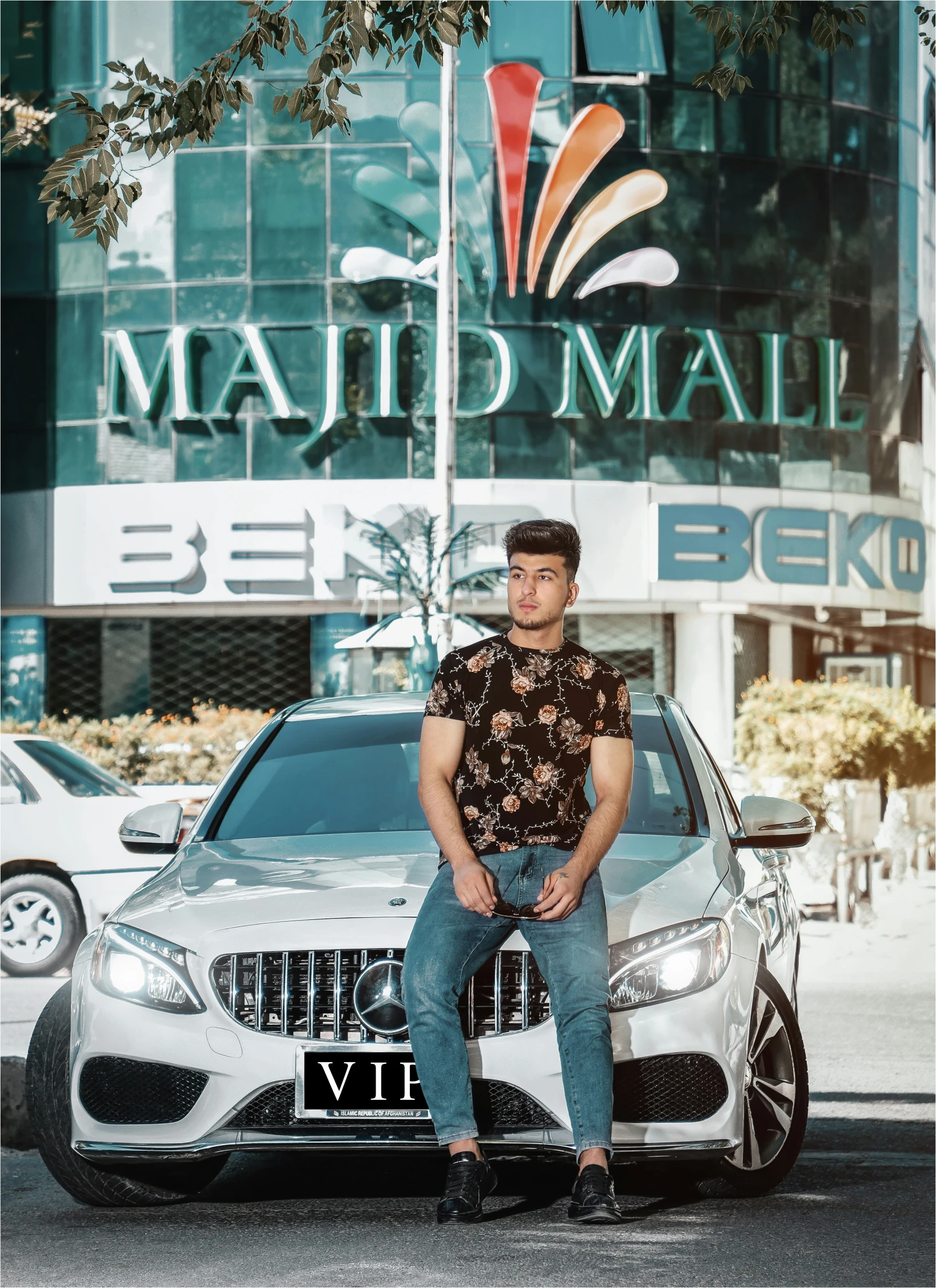 a man sitting on the front bumper of a mercedes benz