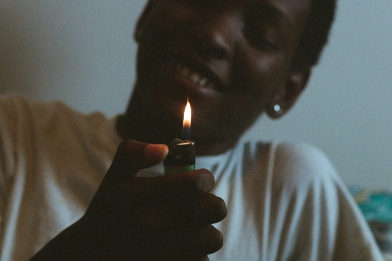 a smiling man holding a lit lighter in his hand