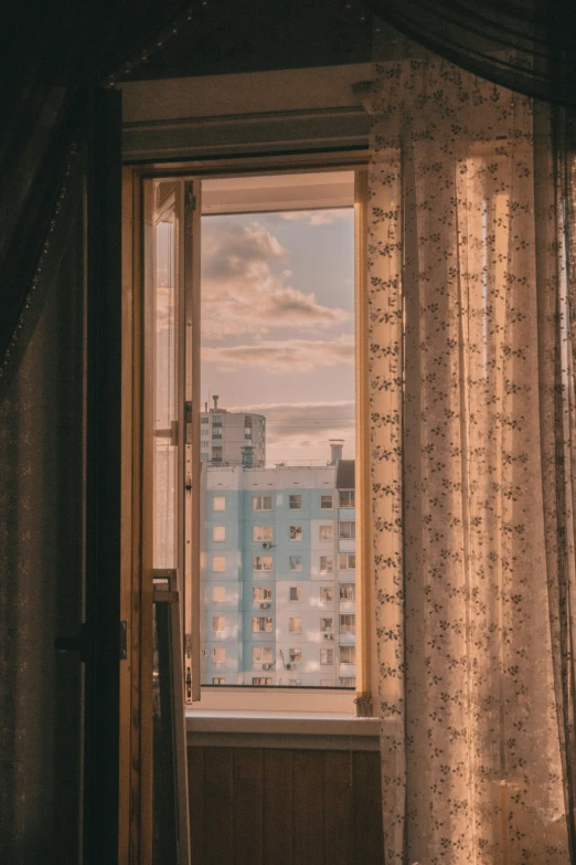 a window with curtain and curtains on it looking out at a city