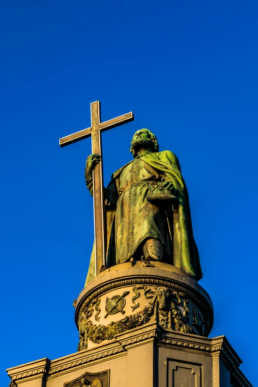 a statue sitting on top of a building with a cross at the top