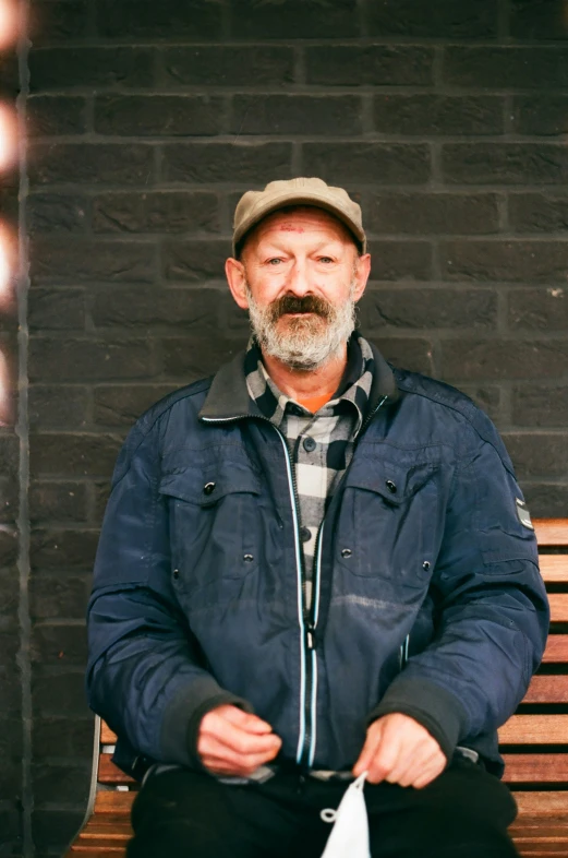 a man with a beard and wearing a hat sitting on a bench