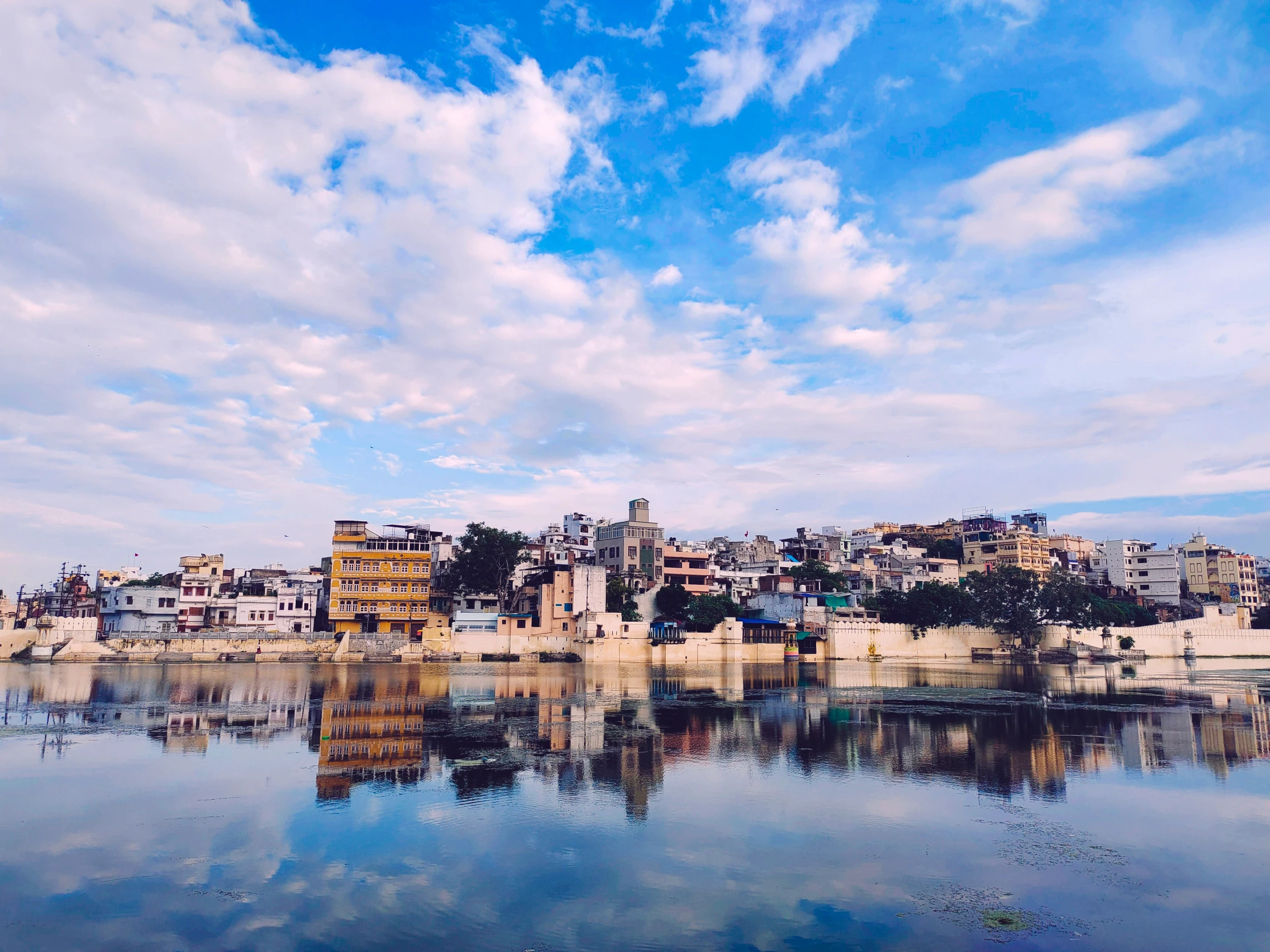 a town is reflected in the still water of a river