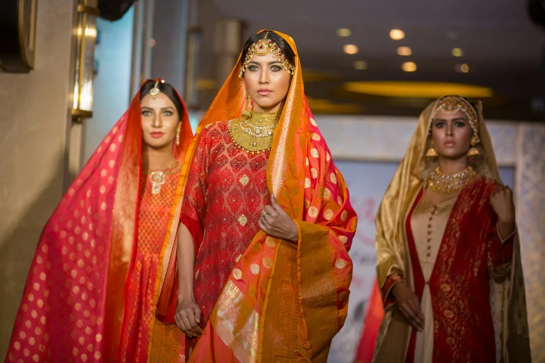 three indian bridal gowns and veils on a runway