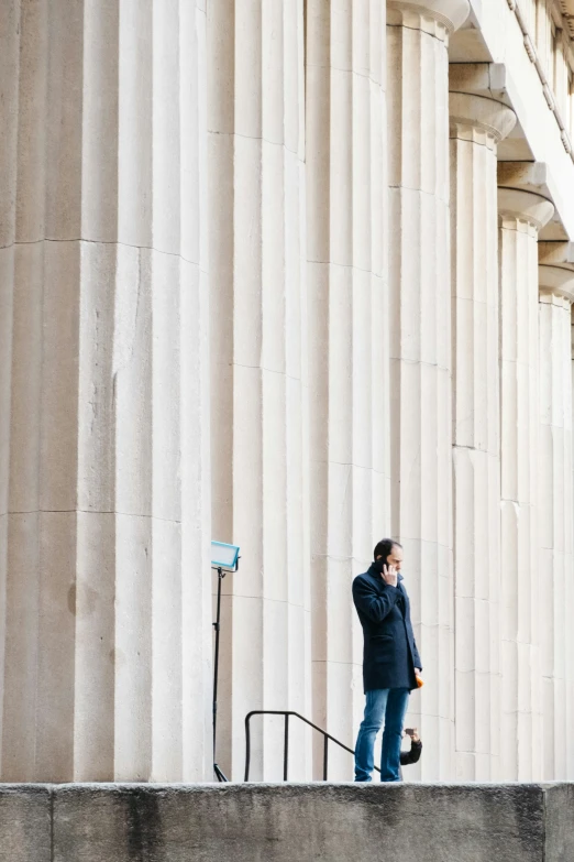 a man stands on some steps in front of a columned building