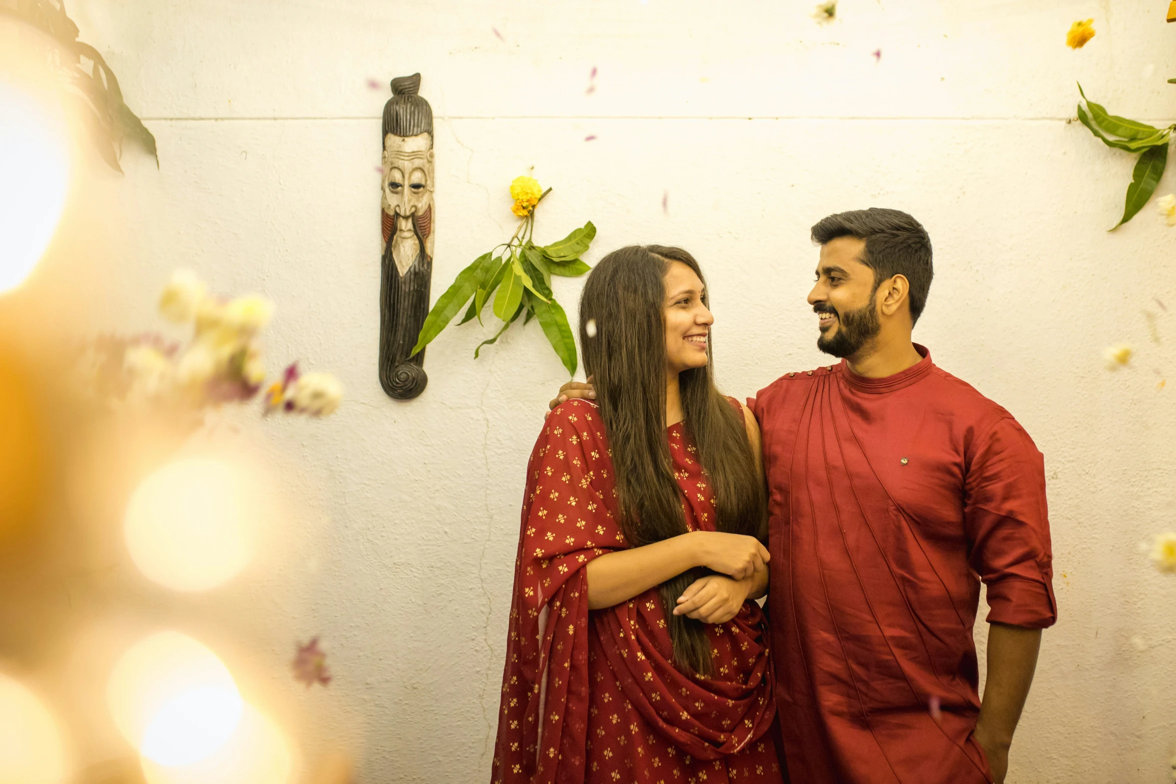 a man and woman smile in front of flowers