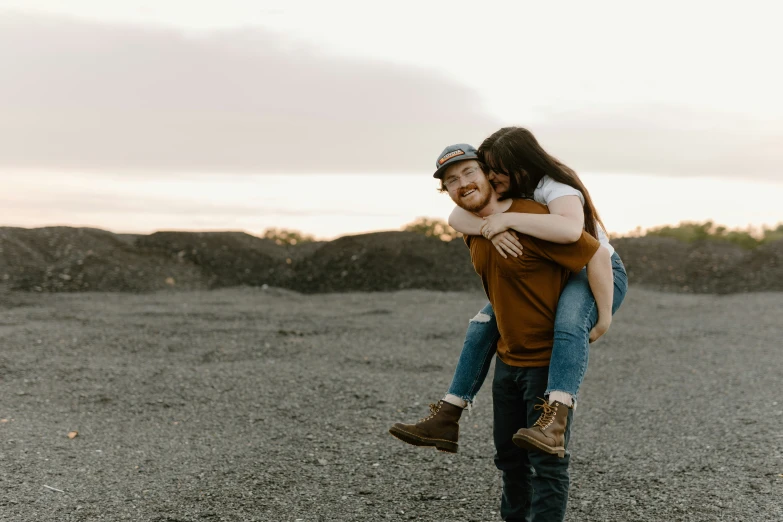 a man and woman standing on a beach one piggyling the other