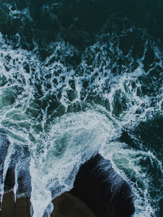 view from above of waves hitting the beach rocks