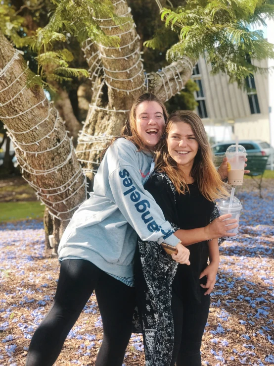 a woman hugging another woman under a tree