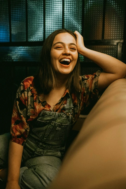 woman sitting on bed laughing next to window