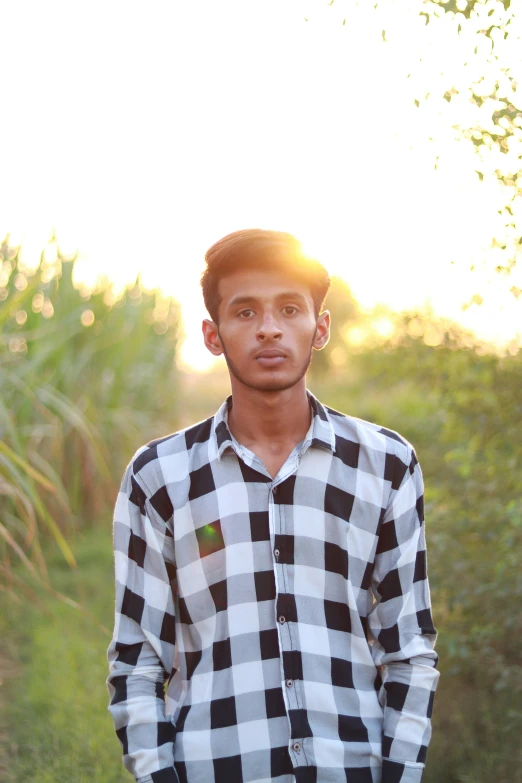 a man in a checkered shirt standing in a field