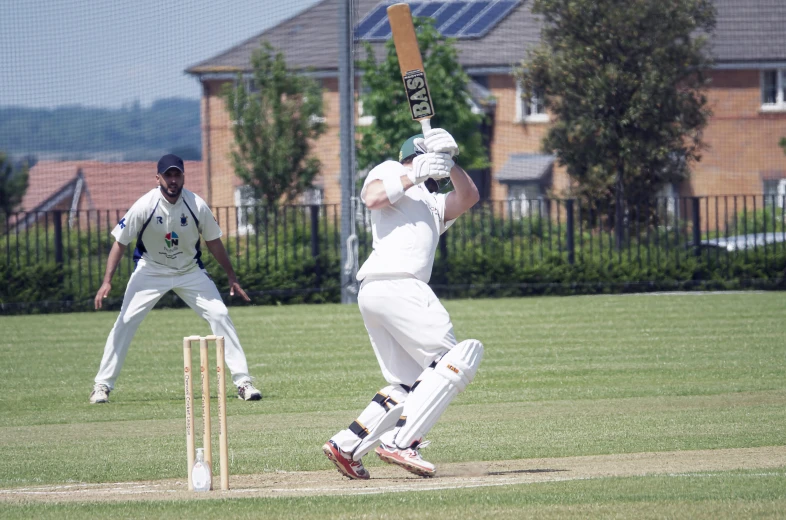 a man playing cricket while another plays the ball